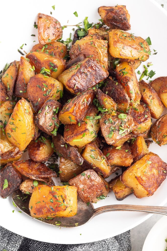 crispy herb roasted potatoes in serving bowl with spoon