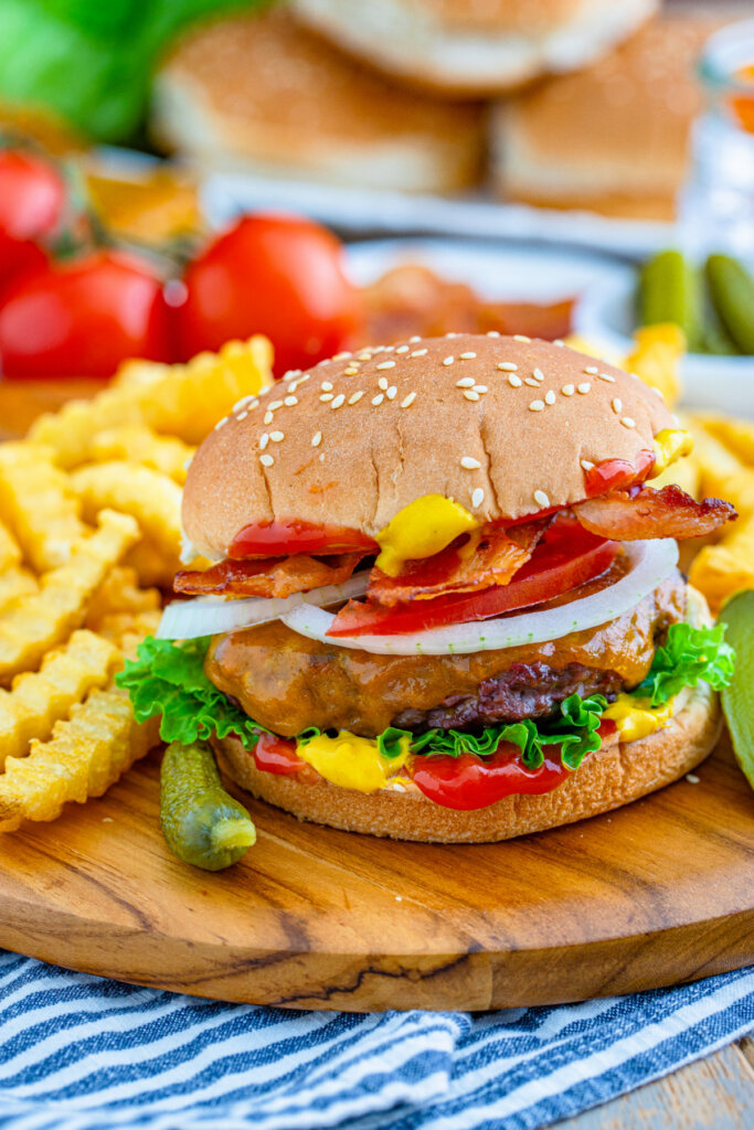 venison burger on wooden cutting board with fries on the side