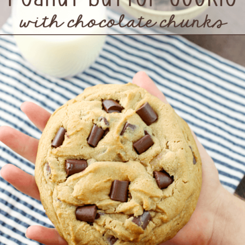 Giant Peanut Butter Cookie with Chocolate Chunks in someone's hand with a glass of milk.