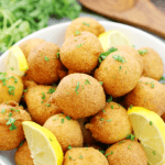 Classic Hushpuppies in a white bowl with fresh lemons.