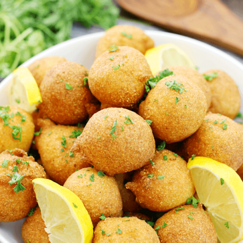 Classic Hushpuppies in a white bowl with fresh lemons.