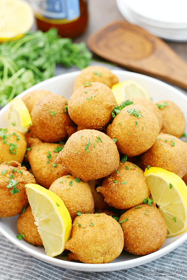 Classic Hushpuppies in a white bowl with fresh lemons.