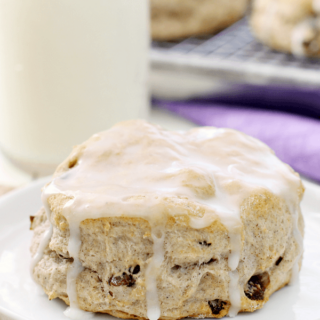 Cinnamon Raisin Biscuit on a white plate with a glass of milk.