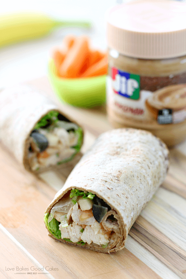 PB Apple Chicken Salad Wraps with the ends opened up to see the ingredients. Close up with a jar of Jif in the background.