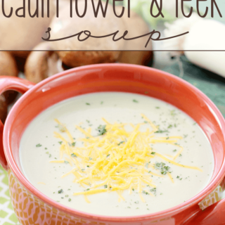 Creamy Cauliflower and Leek Soup in a red bowl with cheese.