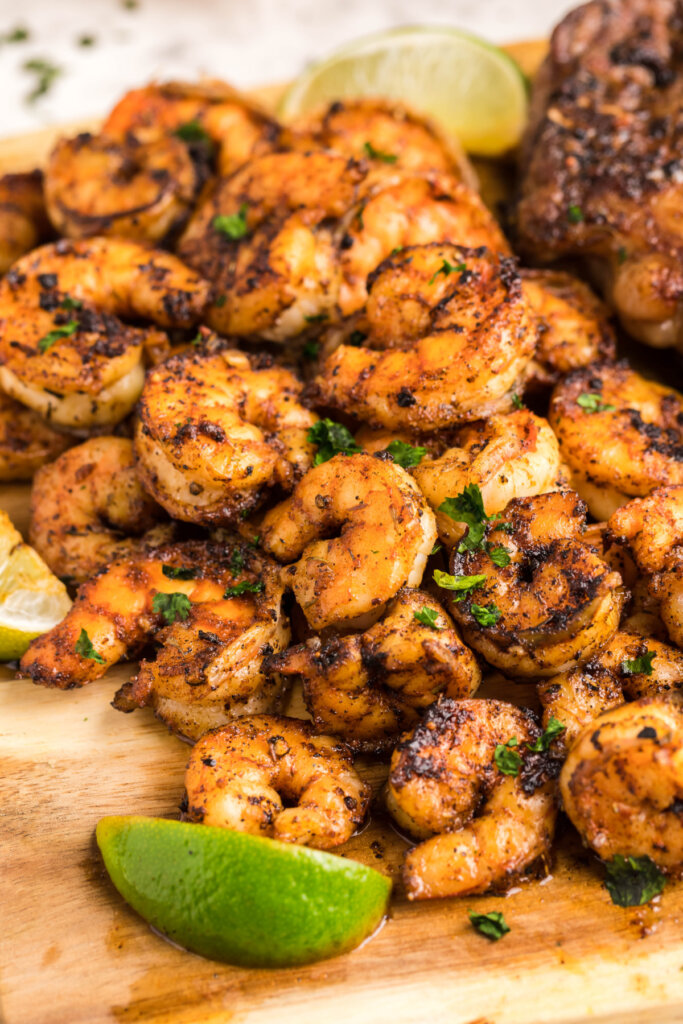 blackened shrimp piled on a wooden board