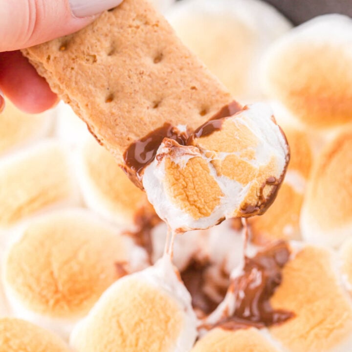 graham cracker scooping chocolate and marshmallow mixture