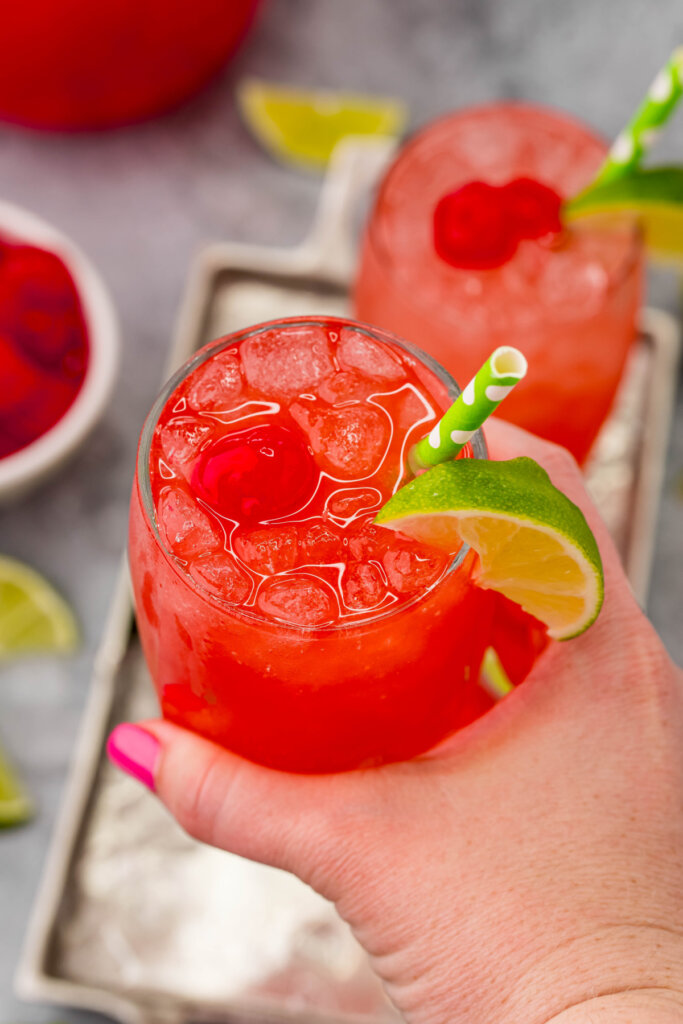 hand holding a glass of cherry limeade