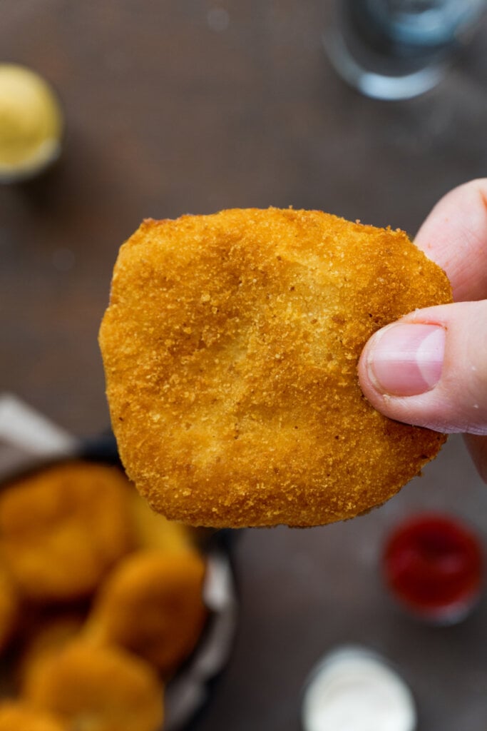 hand holding a single chicken nugget