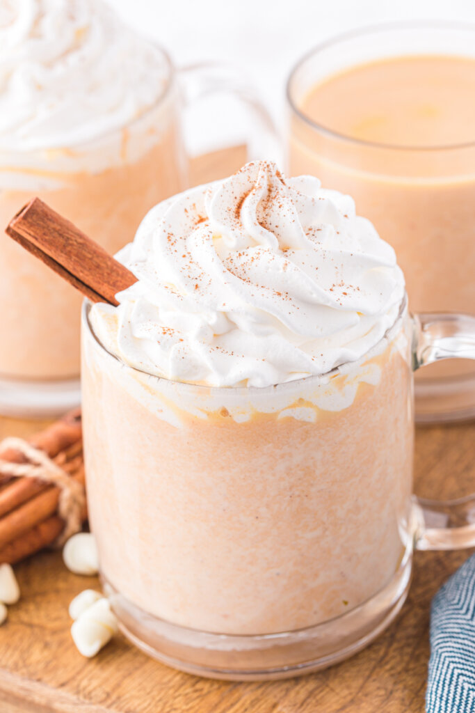 clear glass of pumpkin spice white hot chocolate topped with whipped cream