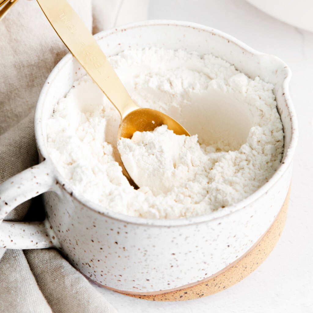 measuring spoon in a clay bowl of cake flour