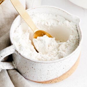 measuring spoon in a clay bowl of cake flour