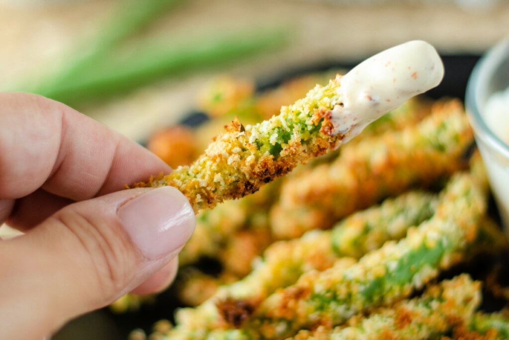 hand holding a green bean fry with dipping sauce on it