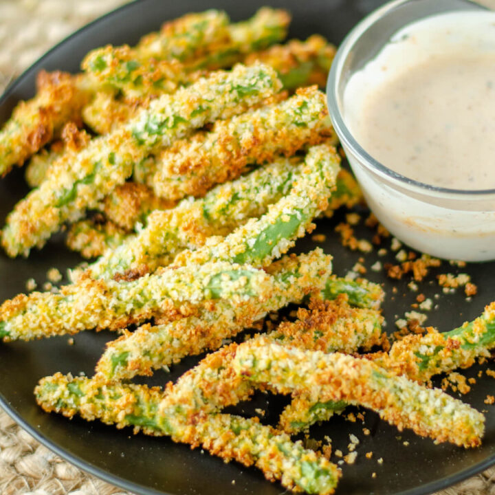green bean fries with dipping sauce on black plate