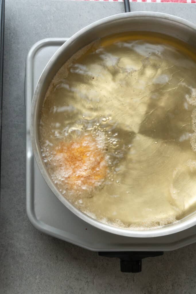 Breaded homemade chicken nugget frying in hot oil until golden brown.
