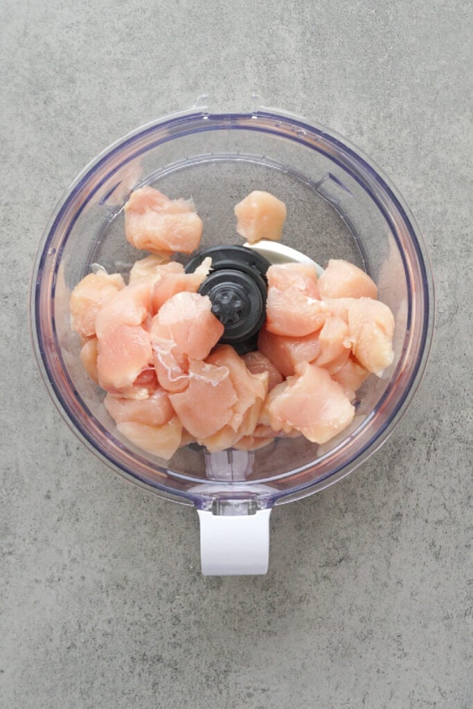 Cubed chicken breast in a food processor before making homemade chicken nuggets.