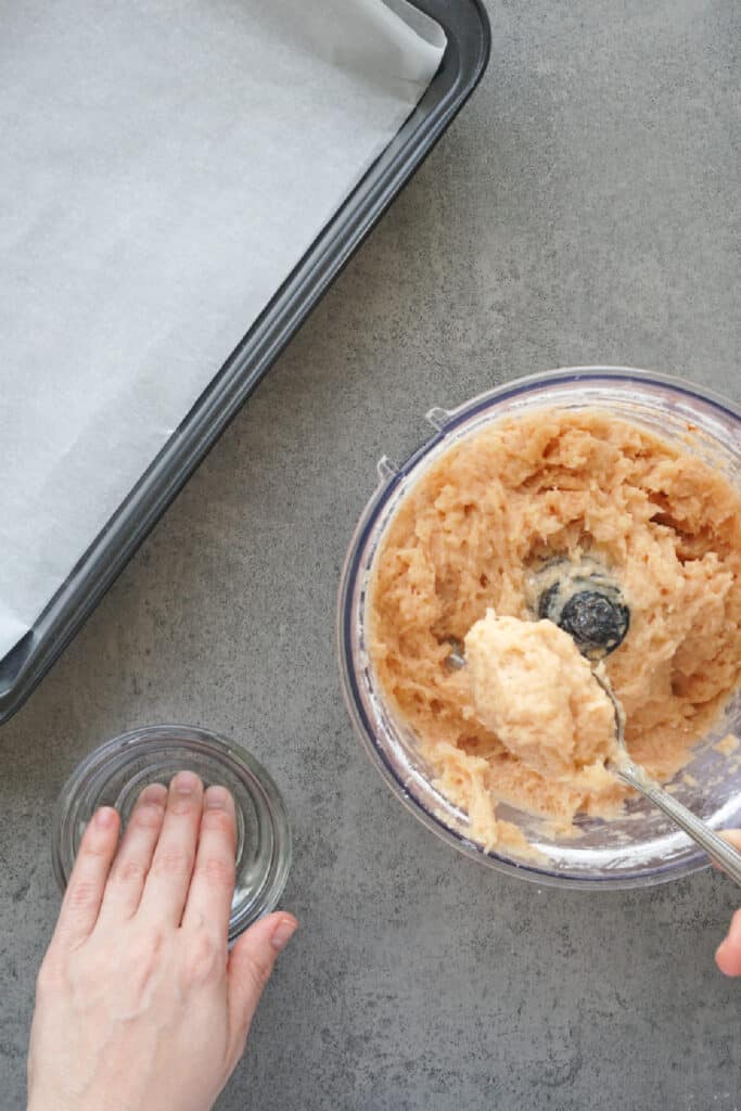 Scooping portions of the chicken mixture to shape homemade chicken nuggets.