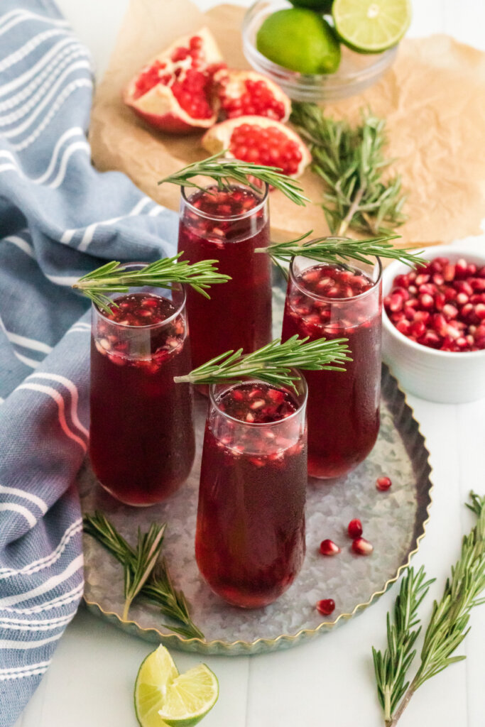 four pomegranate mimosas on metal serving tray