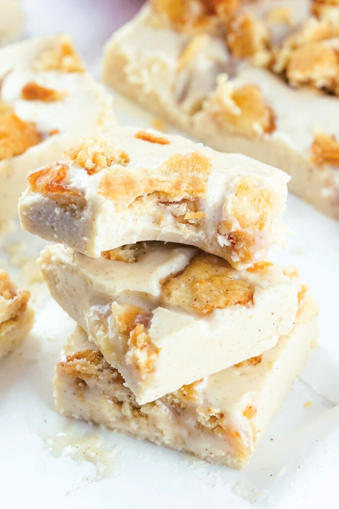 three squares of apple pie fudge stacked with a bite taken out of the top one