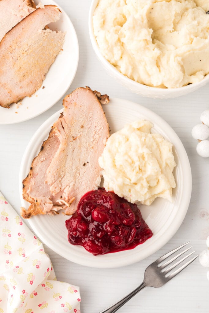 plate of food with sliced turkey, mashed potatoes, and cranberry sauce