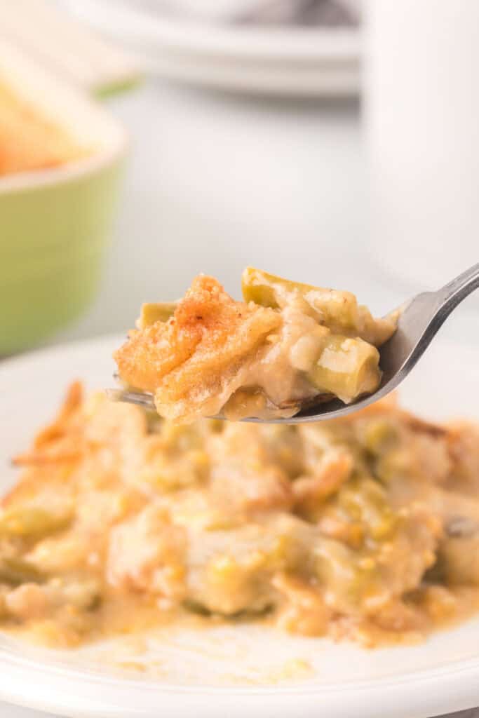 Fork holding a bite of creamy green bean casserole with green beans and crispy fried onions