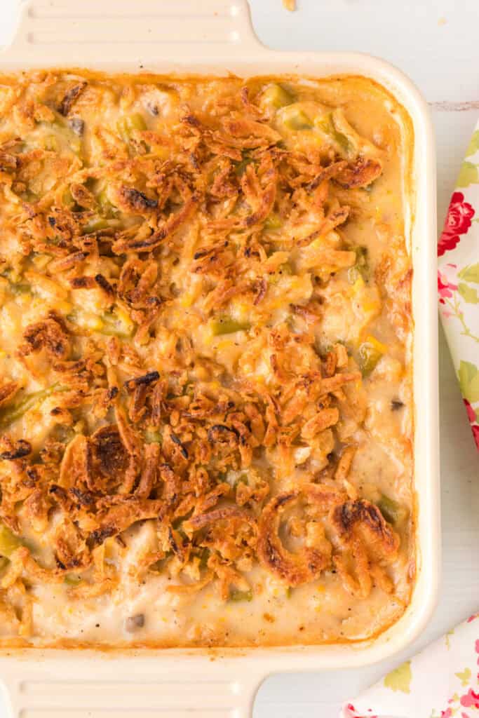 Close-up of creamy green bean casserole with cheddar cheese, green beans, and crisp golden fried onions