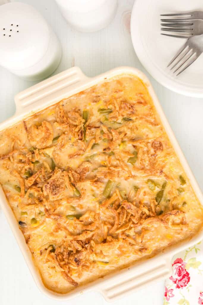 Baked green bean casserole with a golden crispy fried onion topping in a cream-colored baking dish