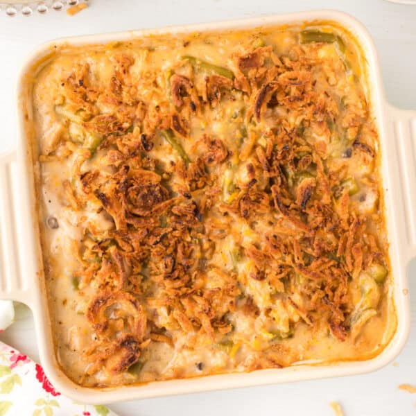 Classic green bean casserole topped with crispy fried onions in a cream-colored casserole dish