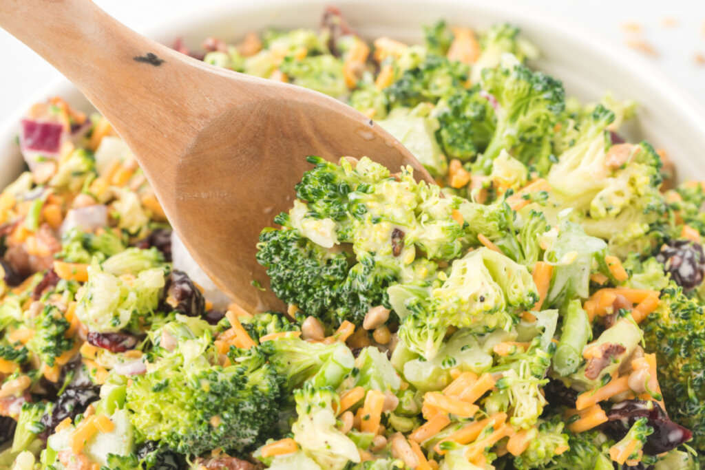 serving spoon sccoping broccoli salad out of a bowl