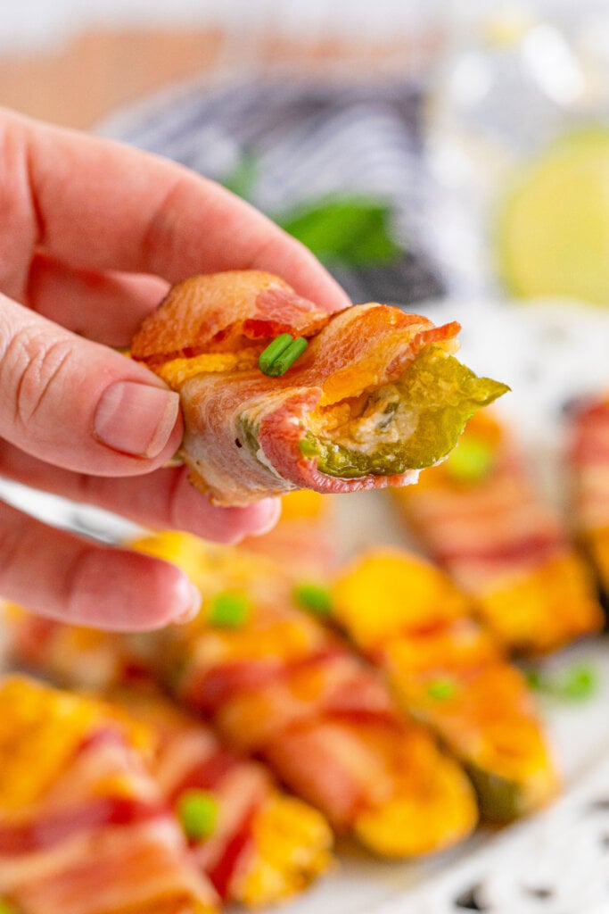 hand holding jalapeno poppers with a bite taken off