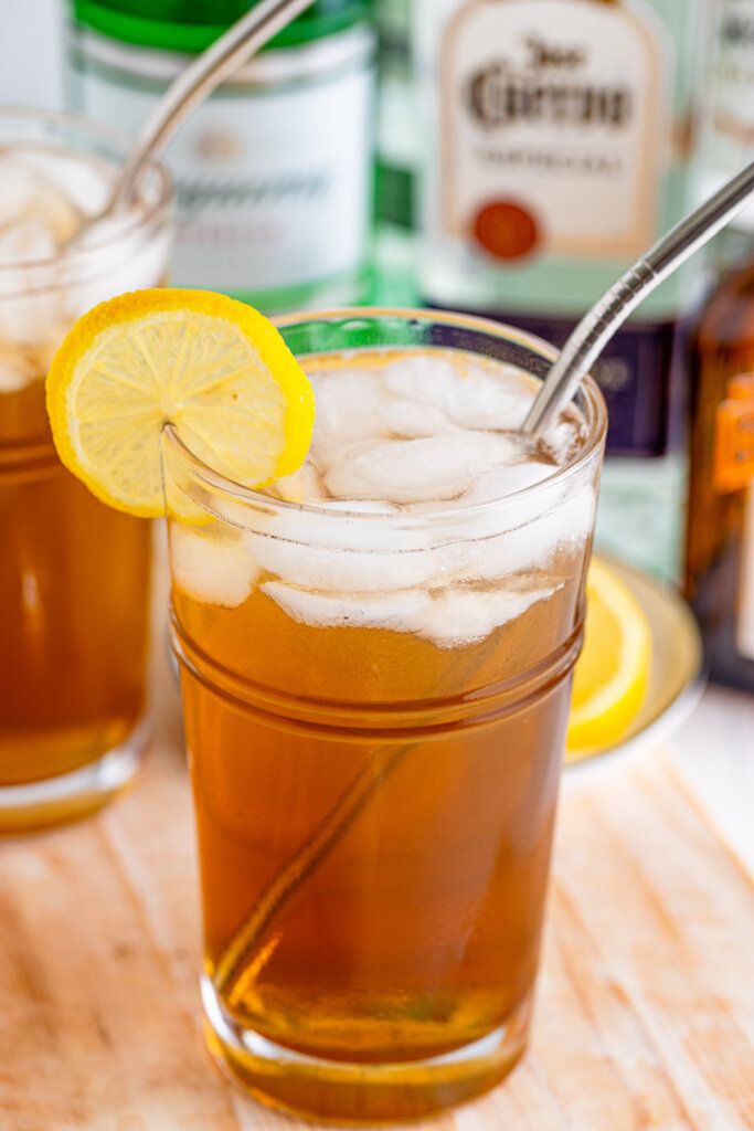 long island iced tea with alcohol bottles in background