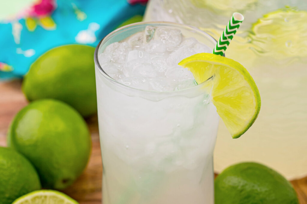 glass of limeade with a straw and lime wedge