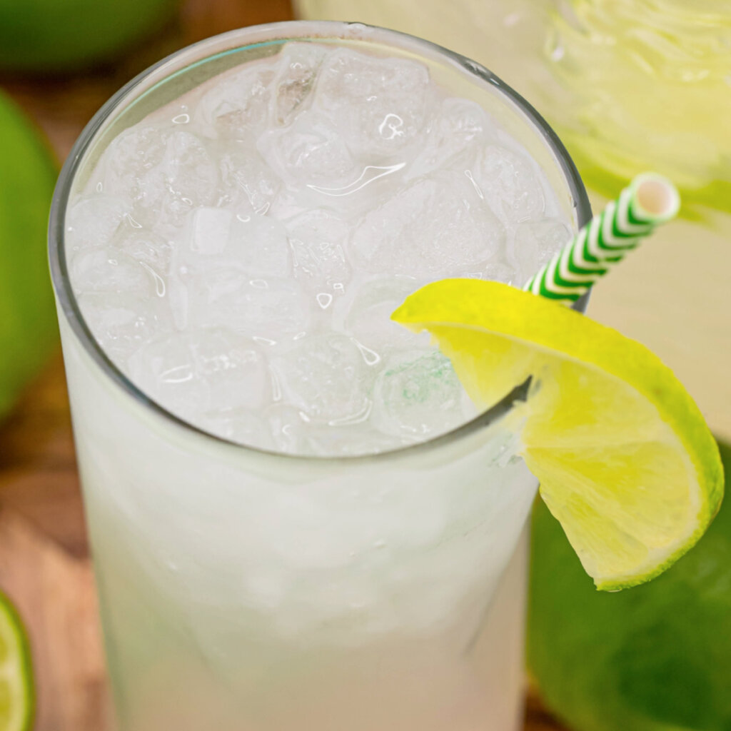 glass of limeade with a straw and lime wedge