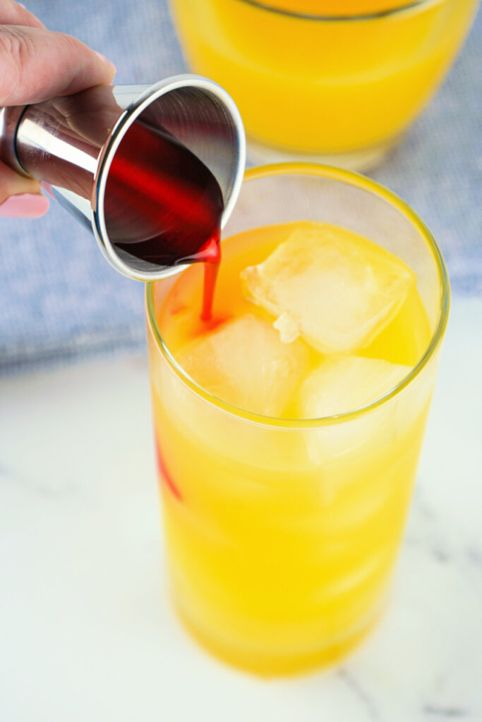 pouring grenadine into cocktail