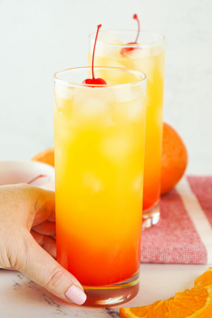 hand holding a tequila sunrise cocktail