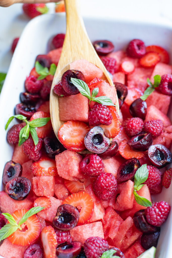 watermelon berry fruit salad in dish with wooden spoon