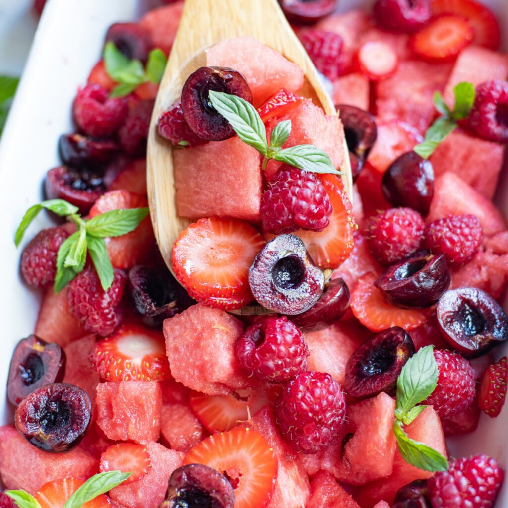 wooden spoon scooping up watermelon berry fruit salad