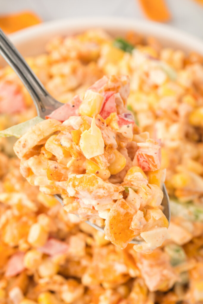 closeup of fritos corn salad on spoon over bowl with salad