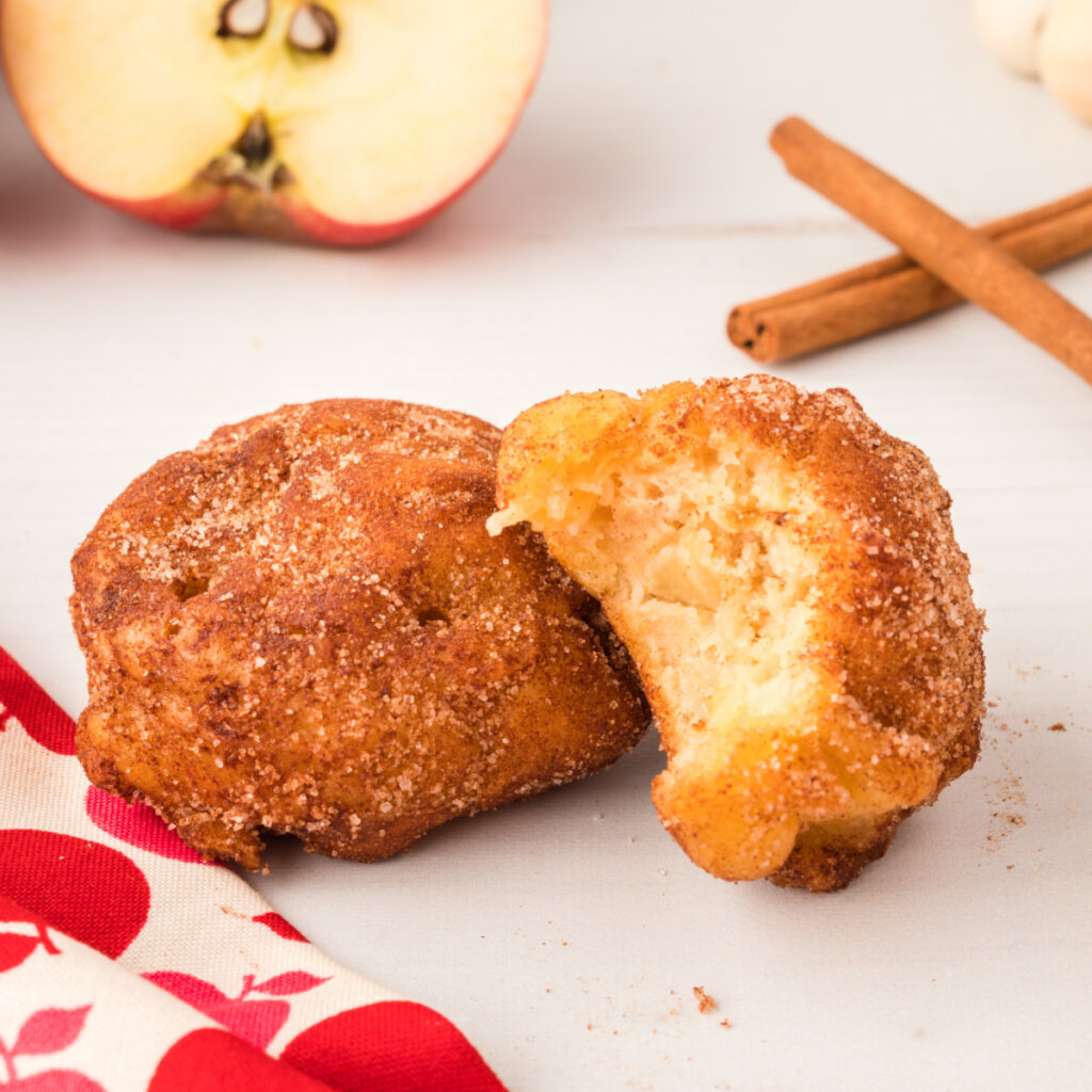 two apple fritters one with a bite taken out