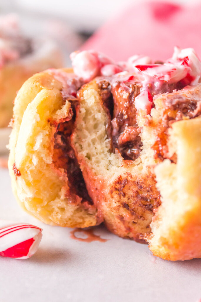 closeup of a candy cane cinnamon roll with a bite taken out showing the inside
