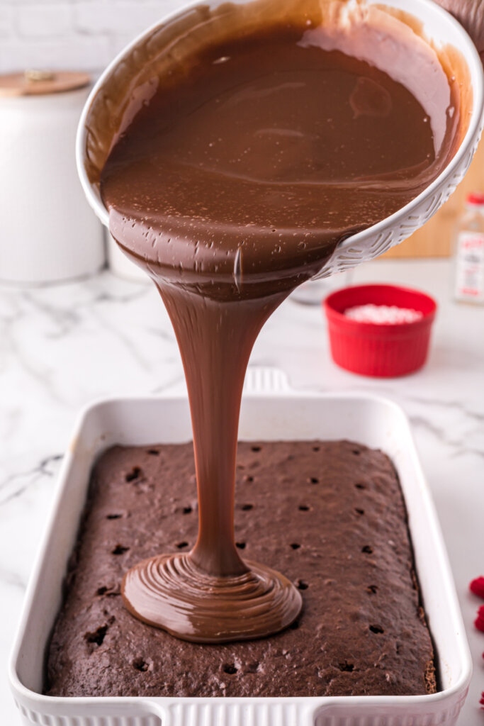 pouring the chocolate filling over the poked cake