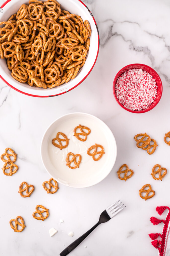 pretzels being dipped in melted white chocolate