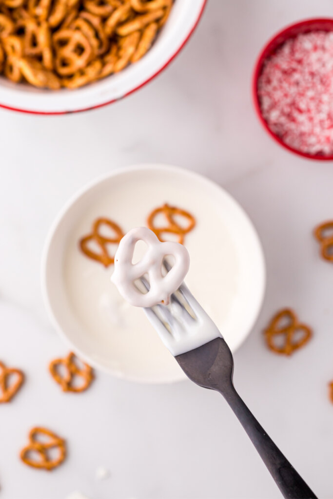 letting the excess chocolate drip off the pretzel