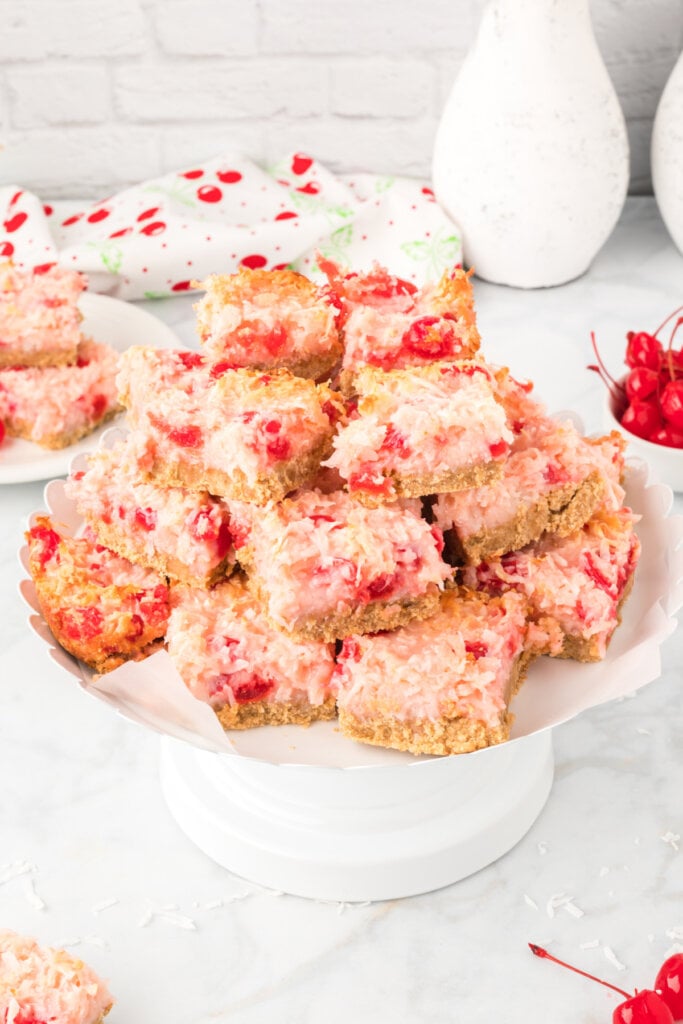 cherry coconut magic bars stacked on cake plate