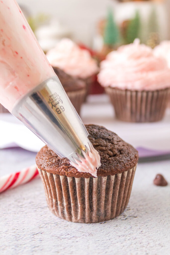 adding peppermint candy cane frosting to a chocolate cupcake