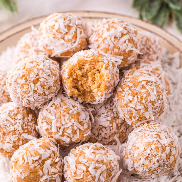 coconut snowballs stacked on plate with bite taken out of one snowball