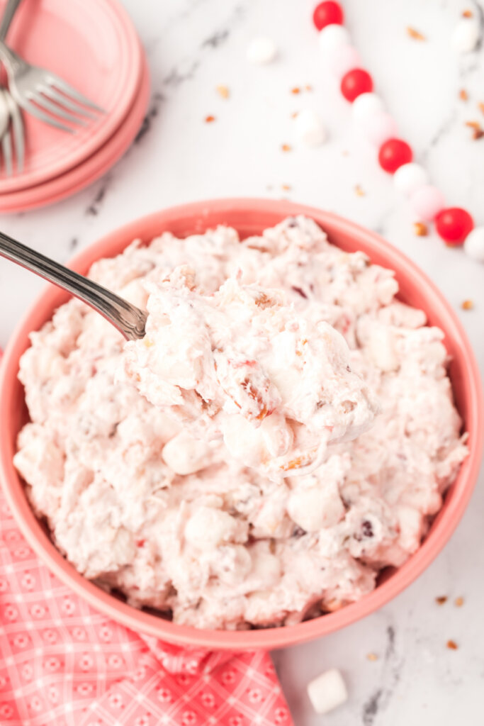 cranberry fluff salad in pink bowl with a spoon