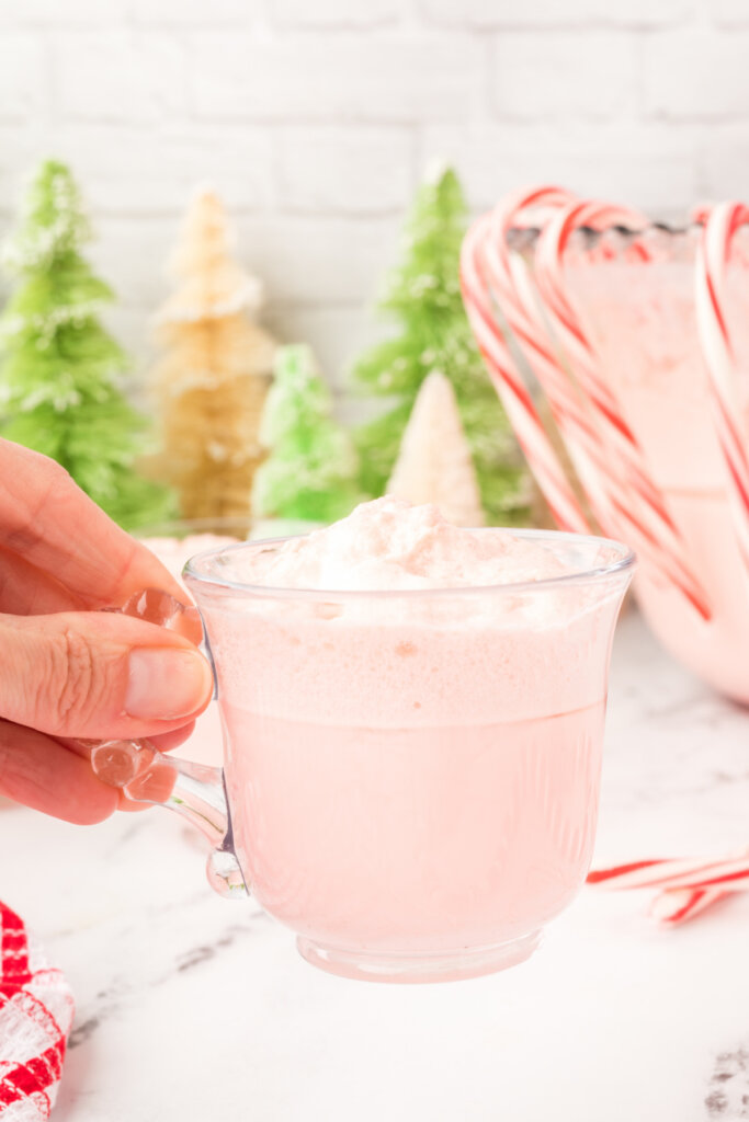 hand holding a glass full of festive peppermint eggnog punch