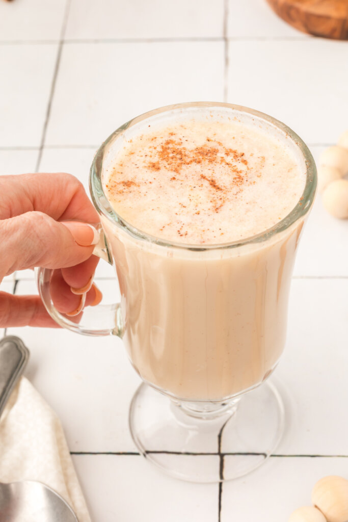 hand holding a glass filled with hot buttered rum mix