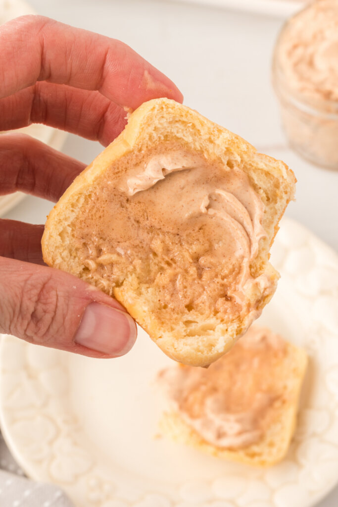 hand holding a copycat texas roadhouse roll spread with cinnamon butter